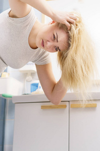 金发女人有问题，油腻油腻的头发在浴室。 女性显示头皮划伤自己的头发，脱发头屑问题。