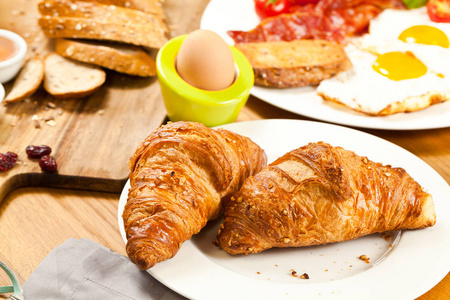 近距离观看新鲜美味的早餐，牛角面包和煮熟的鸡蛋放在木桌上