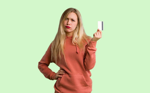 年轻女孩在绿色背景下不带钱的信用卡