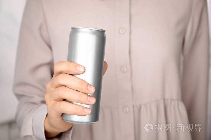 女士手持铝罐与饮料模糊背景特写设计空间