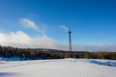 白雪覆盖了群山。 雪中的松树。 蓝天。 厚厚的白云。 海拔高度。 山叫艾皮特里。 克里米亚山。 金属无线电塔。 旅游业。 在克