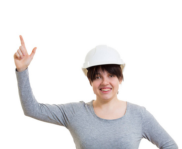 兴奋的年轻女工程师戴着防护头盔，指向食指向上，看着摄像机，在白色背景上与复制空间隔离。