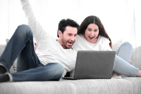 年轻夫妇在他们的笔记本电脑上看电视节目