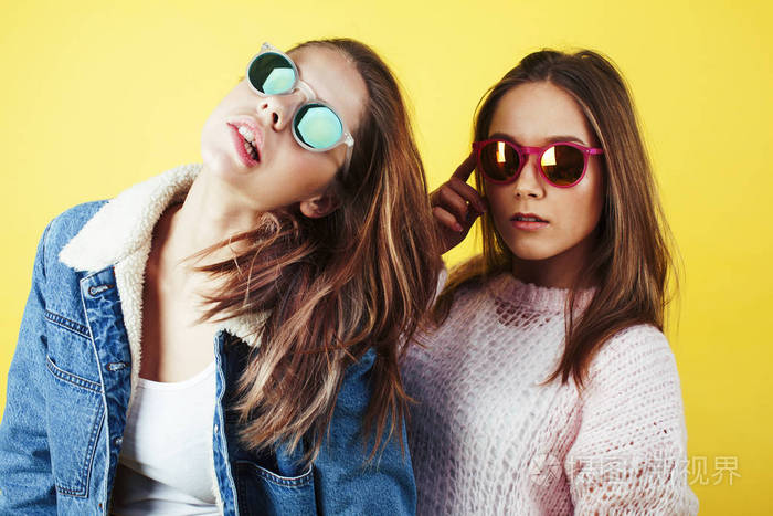 生活方式的人概念: 两个年轻漂亮的学校少女开心快乐微笑在黄色背景上