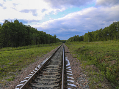 铁路。铁路轨道的背景是绿色的森林和草与明亮的蓝天。没有火车和人的空栏杆。
