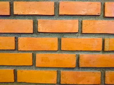橘色砖墙的质感..它们成排排列，交替优美..每块砖周围都是灰色水泥。抽象背景图像，用于壁纸或显示器或背景