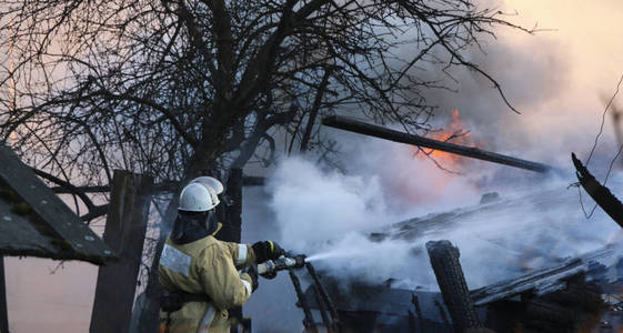 消防员灭火。 烟雾中的消防员用软管里的水浇在燃烧的大楼里。