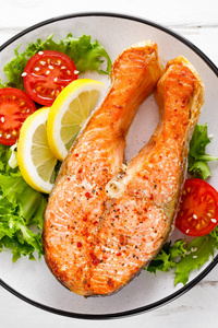 鲑鱼鱼排，烤和新鲜蔬菜沙拉与番茄和生菜。 健康的食物。 顶部视图