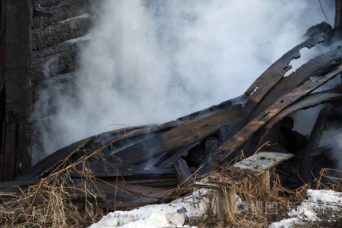 大火烧毁木屋的废墟和遗骸在浓烟中烧焦的木柴