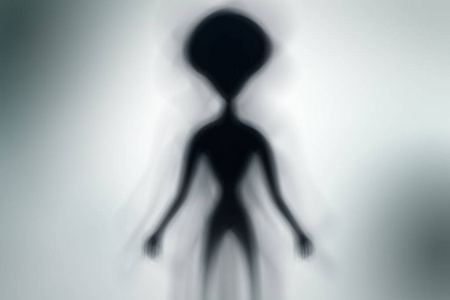 幽灵外星人的轮廓和明亮的光在他身后的UFO概念