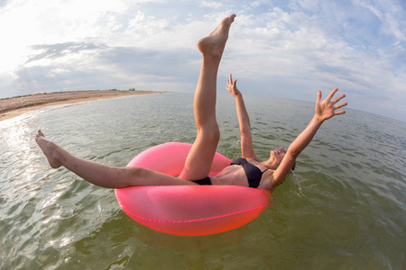 穿着泳衣在海上玩耍的年轻女孩张开双臂和双腿