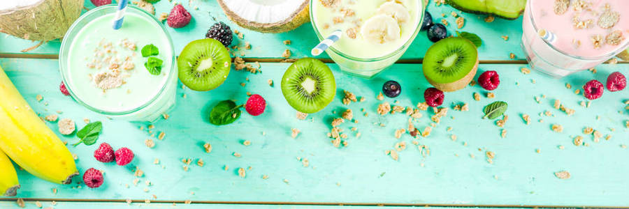 夏季清爽饮料蛋白质奶昔奶昔或冰沙与新鲜浆果和水果浅蓝色桌子复制空间横幅