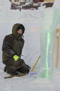 一名穿绿色夹克衫头罩的工人的肖像，从事安排一个冰城