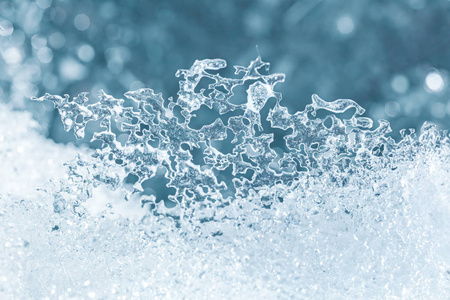 融化的冰雪纹理特写在模糊的蓝光背景下照片