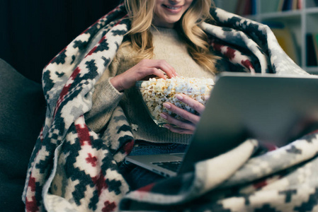 女人用手提电脑看电影，拿着爆米花