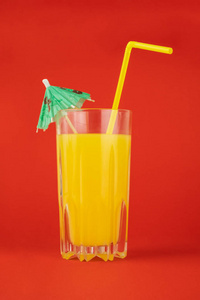 红色背景下的橙色鸡尾酒饮料。 柑橘汁玻璃在明亮极简环境下的图像。