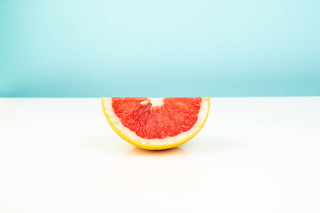 一半的葡萄柚在白色和蓝色背景上。 稀疏明亮环境下柑橘切片的极简主义图像。