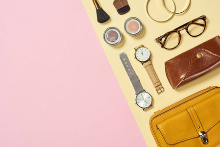 手表的顶部视图，黄色包盒，眼镜，眼影手镯和化妆刷。