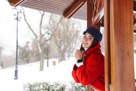 一位美丽的年轻女子在雪地冬季公园森林里散步。