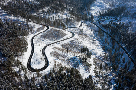 弯曲多风的道路在白雪覆盖的森林，自上而下的鸟瞰。冬季景观。