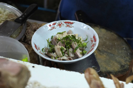 厨师烹饪面条与猪肉和猪肉内脏在当地餐厅泰国街头食品在萨肯纳洪泰国。