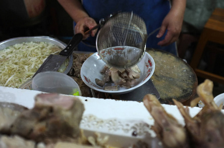 厨师烹饪面条与猪肉和猪肉内脏在当地餐厅泰国街头食品在萨肯纳洪泰国。