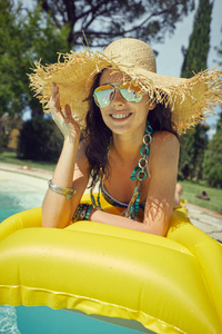 戴着大帽子的年轻女子在游泳池附近放松