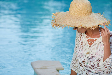 戴着大帽子的年轻女子在游泳池附近放松
