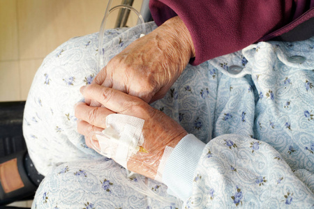 在医院轮椅上静脉滴注的老年女性手