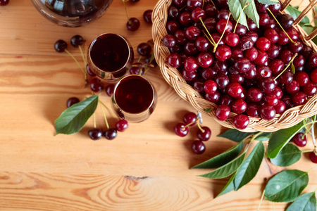 木质背景的樱桃酒或酒，篮子里有成熟多汁的樱桃。