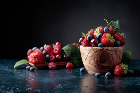 浆果特写彩色什锦混合草莓蓝莓覆盆子和甜樱桃在工作室在黑暗的背景。
