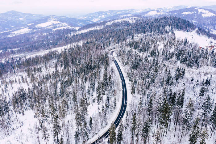 弯曲多风的道路在积雪覆盖的森林自上而下的鸟瞰. 冬季景观.