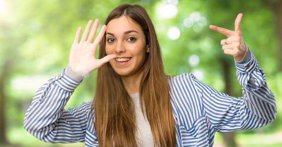 有条纹衬衫的年轻女孩数到七个手指在户外