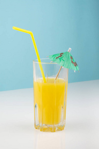 白色和蓝色背景上的橙色鸡尾酒饮料。 柑橘汁玻璃在明亮极简环境下的图像。