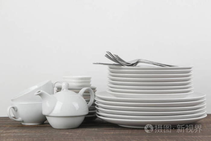 一叠盘子. 棕色木桌上的餐具. 盘子,餐具,杯子和水壶.