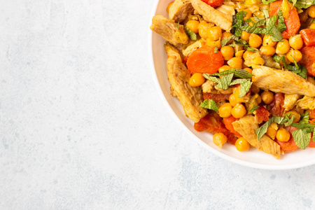 咖喱，鹰嘴豆，火鸡，胡萝卜，韭菜和干杏在一个白色的盘子。健康食品。具体背景。复制空间。