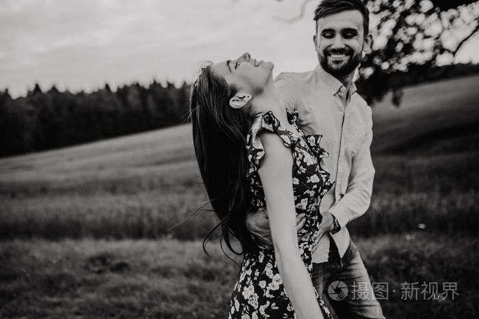 恋爱中的年轻夫妇在草地上散步和拥抱黑白照片