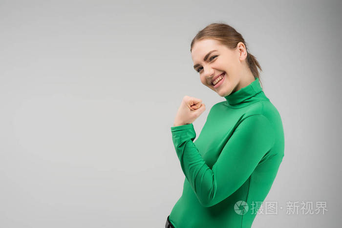 快乐的年轻女人看着相机,用干净的拳头抬起,微笑着. 图像