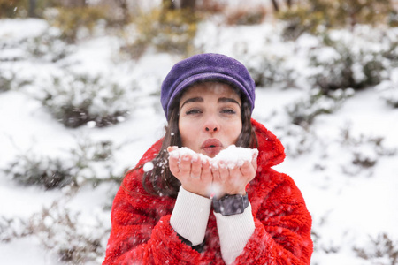 一个漂亮的年轻女人在雪地冬季公园森林里散步的形象。