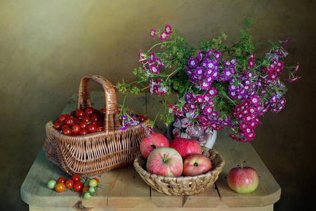 篮子里装着西红柿和苹果，花瓶里装着鲜花的静物生活。