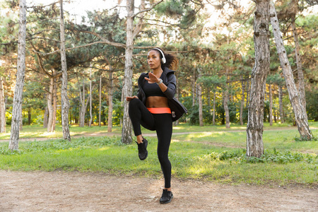 20多岁的精力充沛的女人穿着黑色运动服在绿色公园做运动