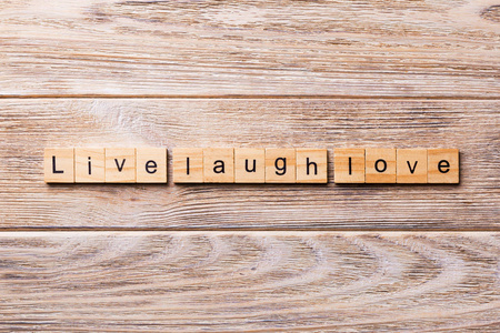 活笑爱字写在木块上。 现场笑爱文字在木桌上为您的设计理念。