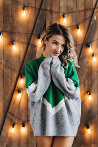 一个的现代金发女人站在一件毛衣的背景下，灯光和木墙