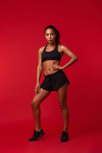 一个美丽的年轻非洲体育健身妇女的形象，摆在红墙背景上。