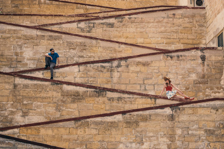 男人和女人坐在城墙上，这是马耳他三大城市的老城区