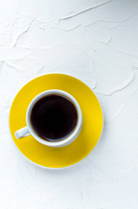白色背景上的黄色咖啡杯。 极简主义。 垂直照片