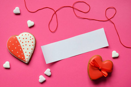 自制姜饼心与一张空纸为您的文字在粉红色背景。 情人节饼干心。 可食用情人节礼物或贺卡概念。
