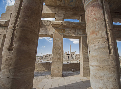 列克索尔埃及卡尔纳克神庙的矮柱大厅中有象形文字雕刻的柱子，背景中有方尖碑