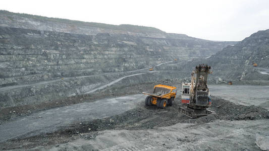 挖掘机在露天矿中用泥土填充自卸车。露天矿矿山的重型机械工程