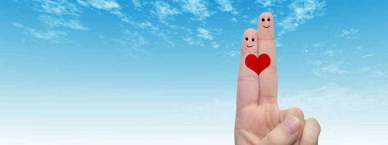 概念或概念人类或女性的双手，两个手指涂有红色的心和微笑的脸在云蓝色的天空背景横幅上